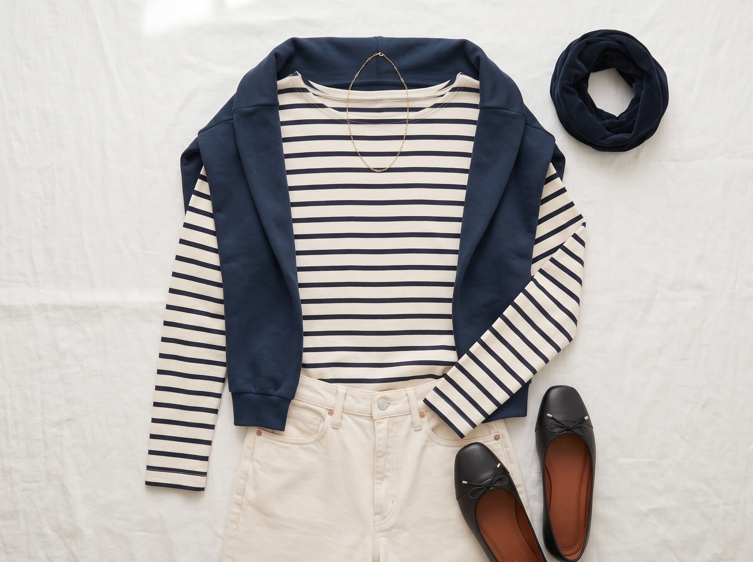 Ringelshirt in Navy-Ecru mit dunkelblauem Sweatshirt, cremefarbener Jeans, Loop und schwarzen Ballerinas