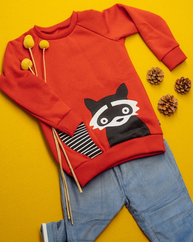 Kinder Outfit mit orangefarbenen Waschbär-Sweater von internaht und blauer gefütterter Cord Hose von Pigeon beides aus 100% Biobaumwolle