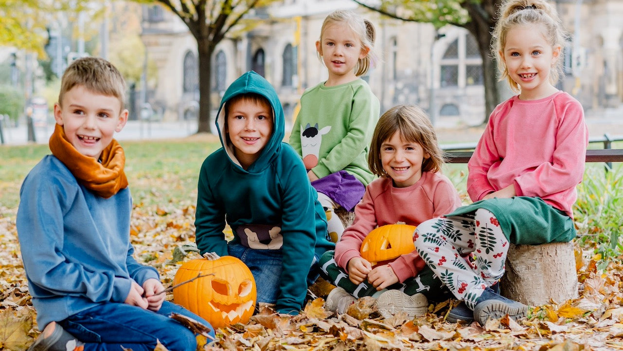 Nachhaltige Kintermode von internaht aus Dresden - fünf fröhlich lachende Kinder in der farbenfrohen Kinderkleidung von internaht in einem herbstlichen Park 